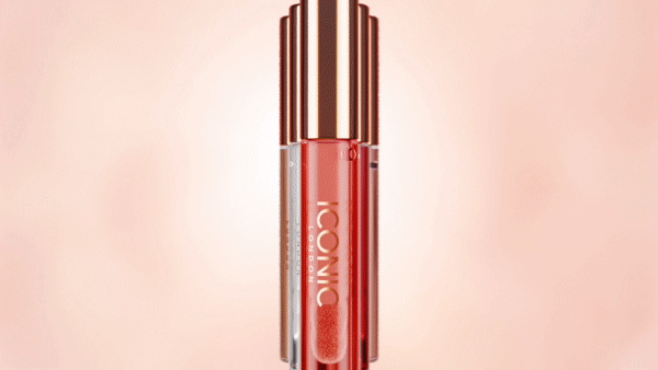 Three tubes of Iconic London lip gloss stand in a row against a light peach background, with light reflections on the bottles.