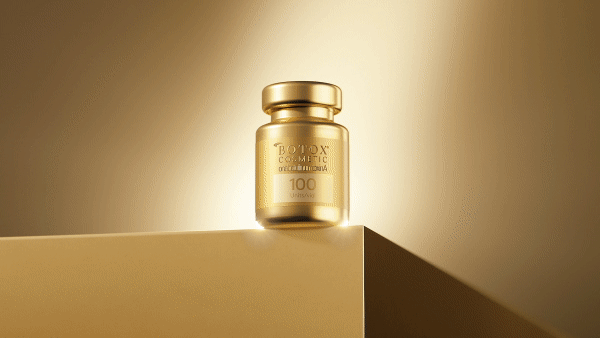 Gold Botox Cosmetic vial is showcased on a gold surface against a gradient gold backdrop. Close-up studio shot.
