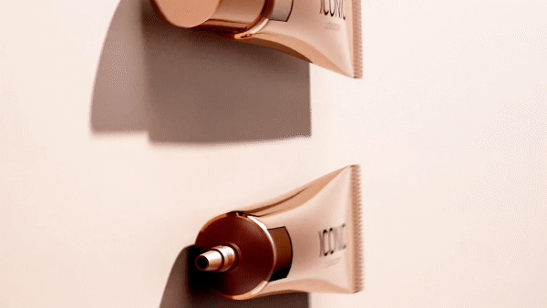 Two tubes of Iconic London Sheer Bronze makeup product on a light peach background. Beauty product shot showcasing bronze makeup.