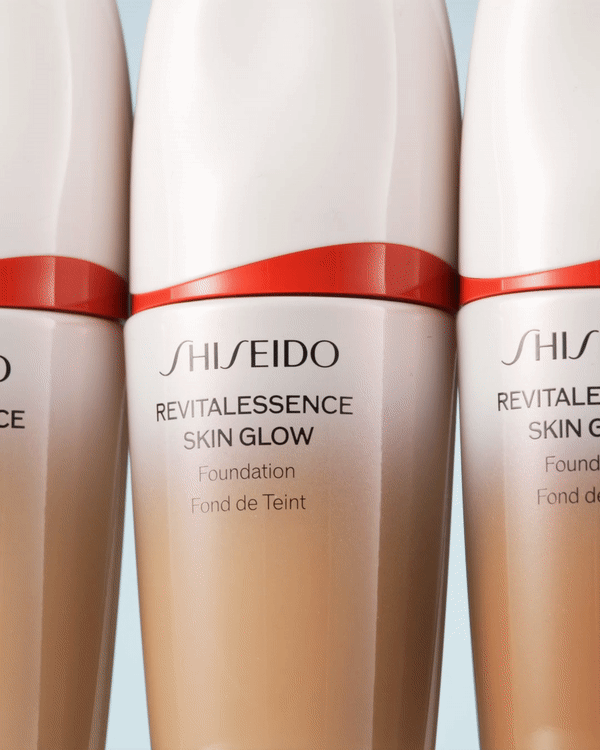 Three bottles of Shiseido Revitalessence Skin Glow Foundation are showcased in a clean product shot against a light blue backdrop.