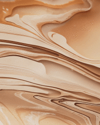 Macro shot of swirling liquid paint textures in shades of beige, cream, and warm brown styled by Allison Ritchie.