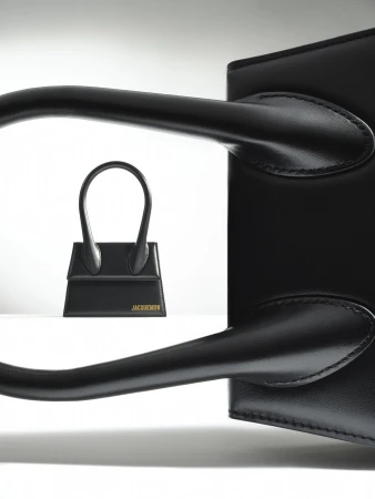 Two black leather Jacquemus bags are displayed against a white backdrop, with a smaller version in front of a larger one.