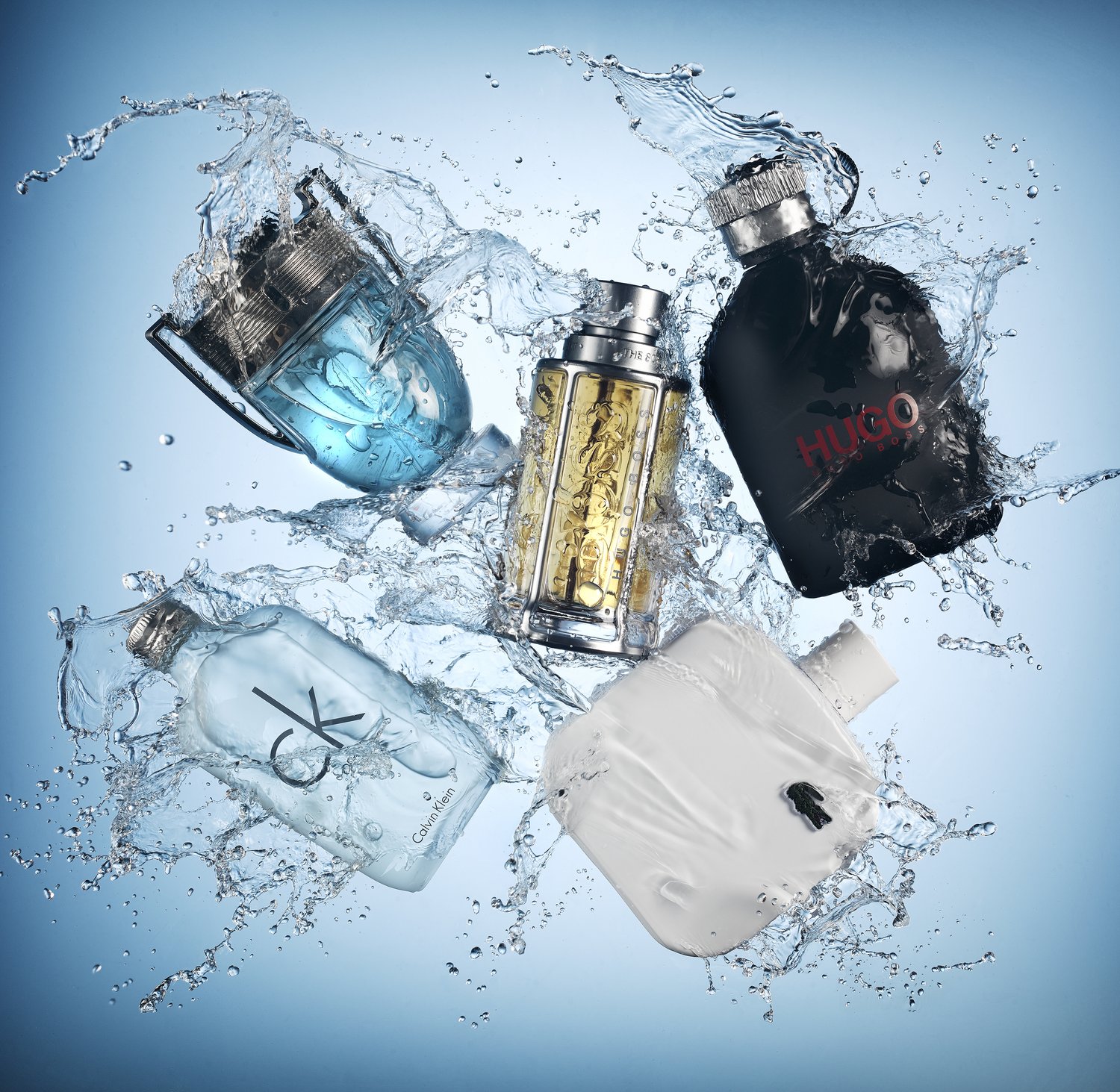 Five diverse perfume bottles arranged with water splashes against a gradient blue background in a product shot for the beauty industry.