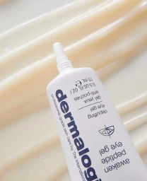 Close-up product shot of a white Dermalogica eye gel tube resting against creamy textured skincare product smears.