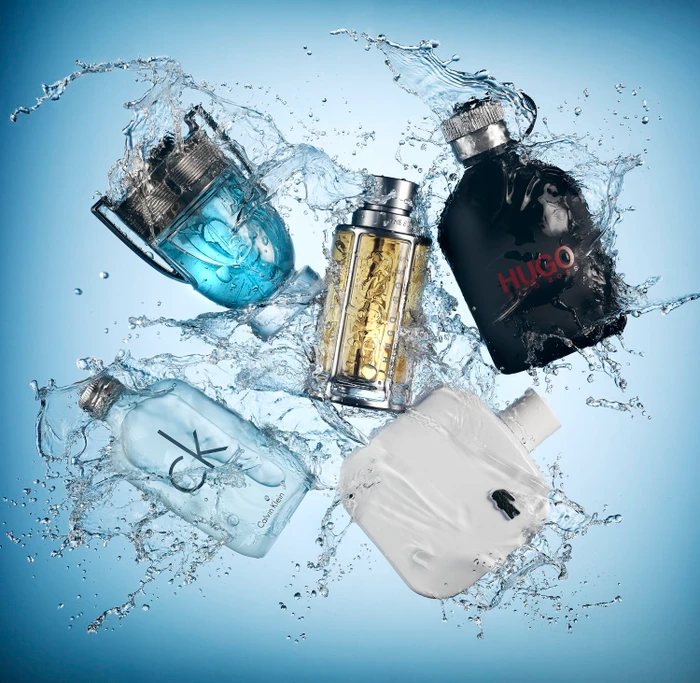 Five different fragrance bottles surrounded by dynamic water splashes against a blue gradient background