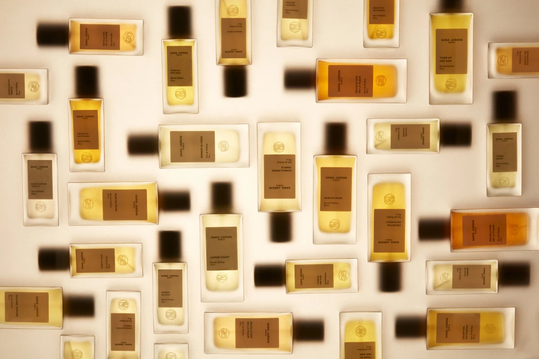 Overhead flat lay arrangement of multiple perfume bottles with amber liquid and dark caps casting soft shadows on white
