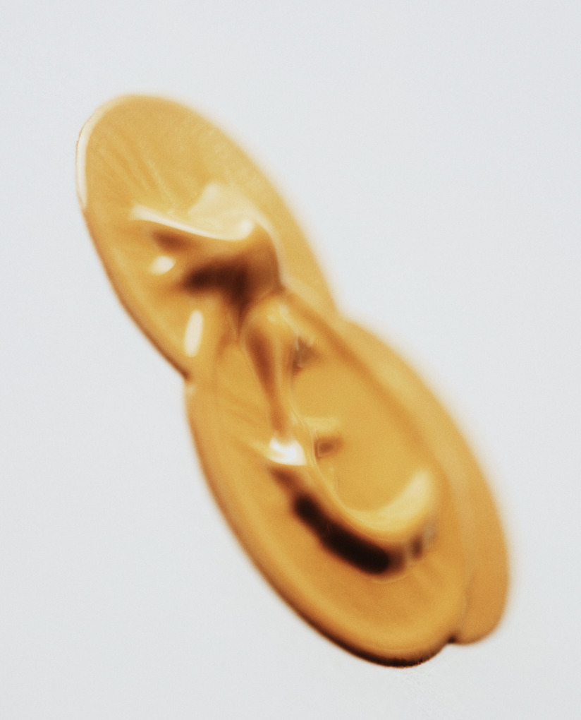 Close-up of an elongated oval capsule in shades of orange and brown, against a white background, suggesting pharmaceutical or supplement product.
