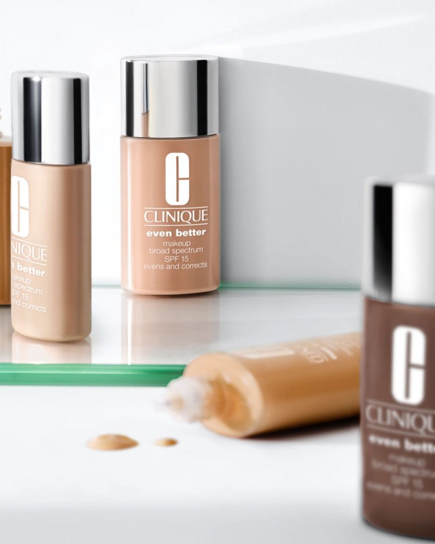 Clinique Even Better makeup foundation bottles in varying shades of brown, arranged on a clear surface against a light backdrop.