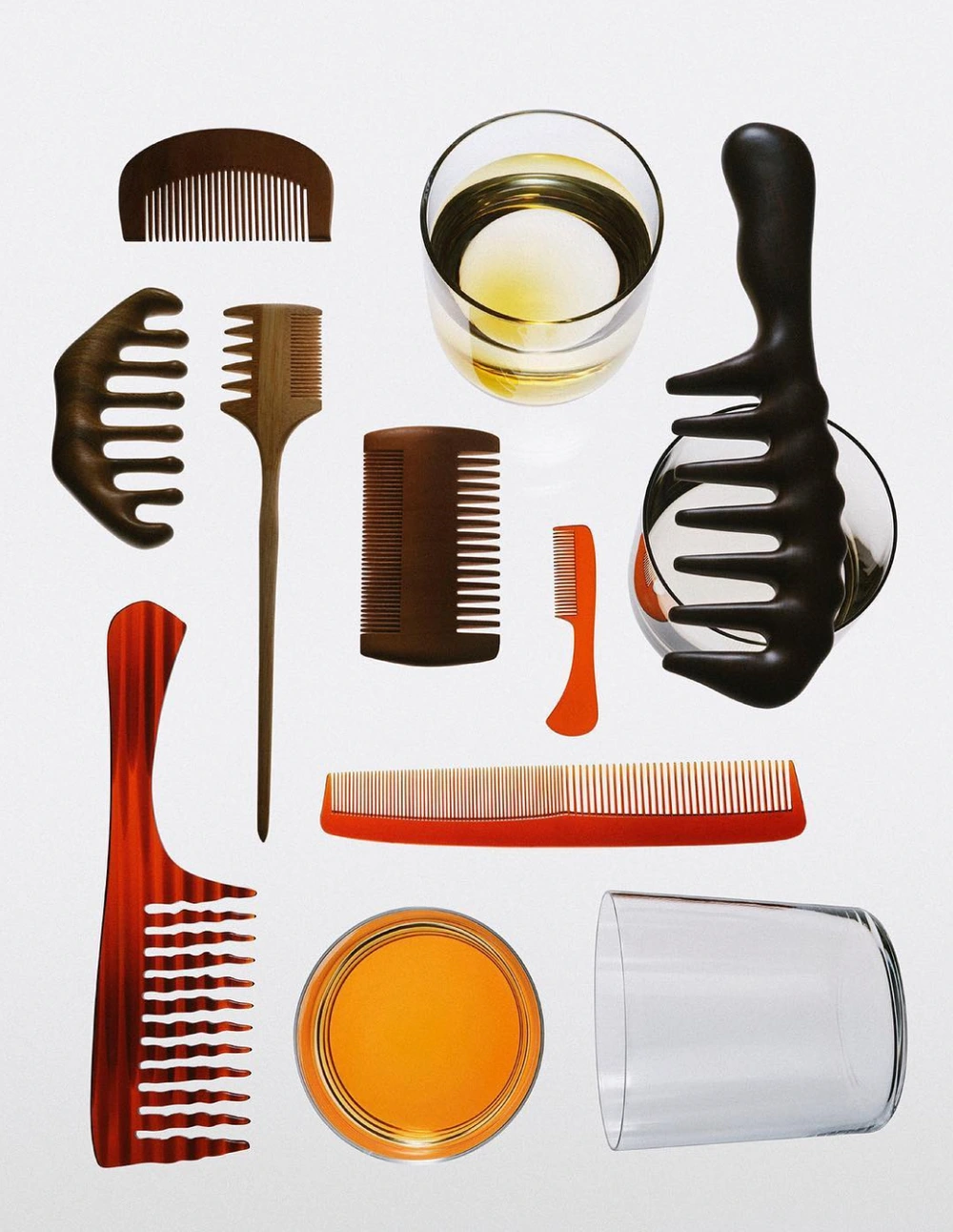 Overhead flat lay of wooden combs, hair picks, and glass tumblers containing amber liquid against a clean white background