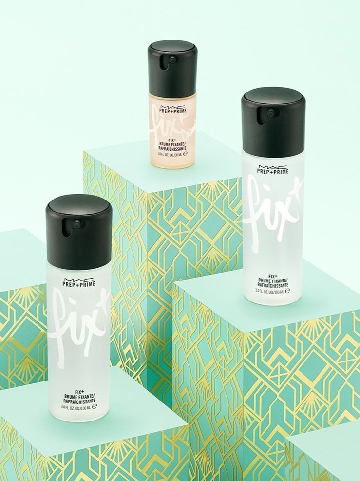 Three bottles of MAC Prep+Prime Fix+ setting spray on art deco pedestals against a light teal backdrop. Product shot.