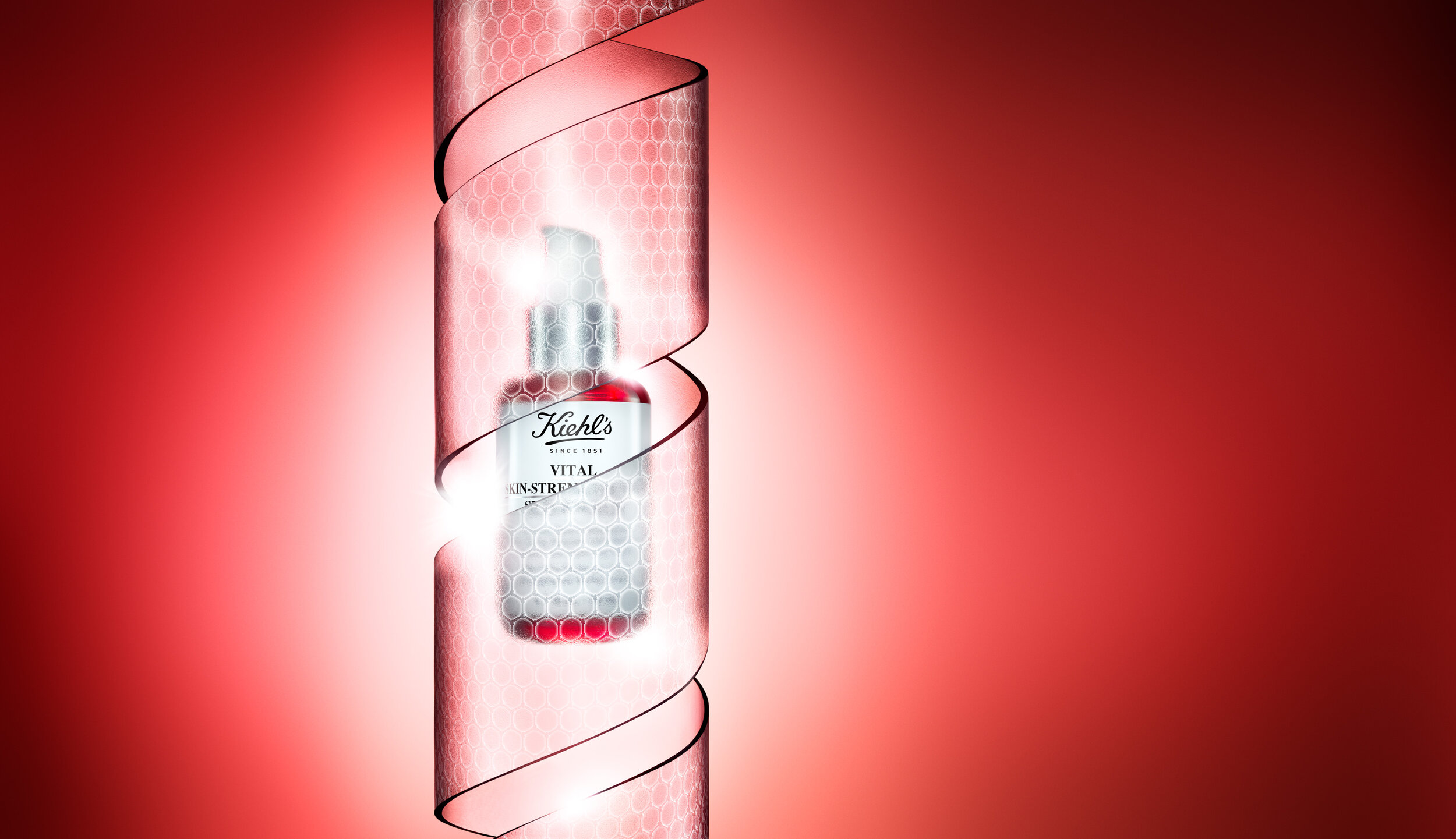 Kiehl's Vital Skin-Strengthening Hyaluronic Acid Serum bottle on a red backdrop, wrapped by ribbon with a honeycomb pattern.