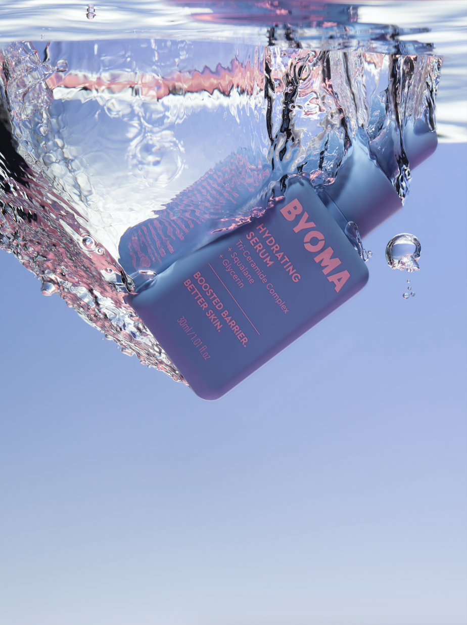 BYOMA Hydrating Serum bottle floats in clear water against a blue backdrop with diffused lighting, perfect for beauty product advertising.