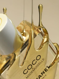 Close-up of golden liquid pouring over a glass perfume bottle in a studio set designed by Sophie Iona