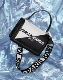 A Karl Lagerfeld black and white handbag with a branded strap resting on a shiny blue crinkled metallic background.