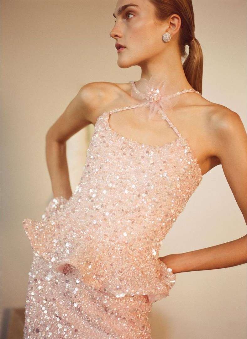 Model in pink sequin halter top wearing a sparkling earring against a warm indoor background by Ryan Brabazon