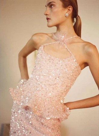 Model in pink sequin halter top wearing a sparkling earring against a warm indoor background by Ryan Brabazon