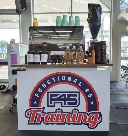 A mobile coffee setup by Pullin Shots in Sydney featuring an espresso machine, syrup bottles, and branded cups.
