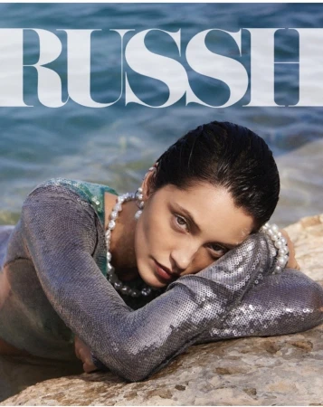 Woman with pearls in water, wearing sequin top, lying on rock near ocean, shot for fashion, beauty and entertainment industries.