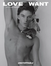 Portrait of Jordan Barrett holding leafy stems with a pearl necklace against a plain background