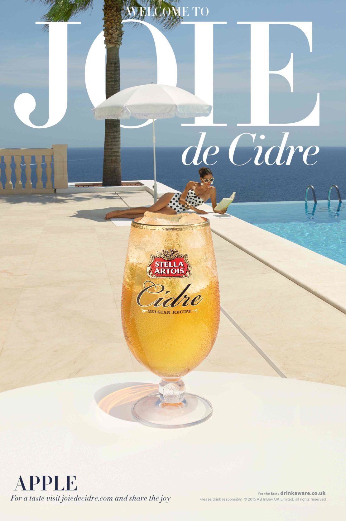 Stella Artois Cidre ad featuring a glass of beverage, a woman reading, and a white parasol by a pool with ocean view.