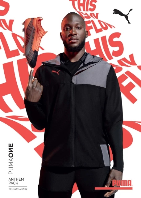 Romelu Lukaku poses in a Puma jacket with a Puma soccer cleat balanced on his finger, showcasing the brand's Anthem Pack collection.