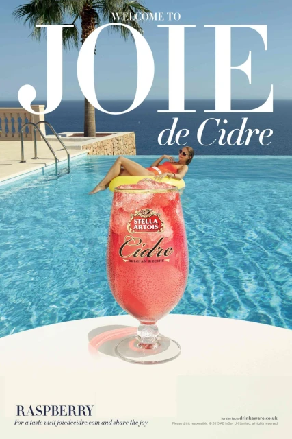 Beverage ad with a cocktail glass in front of a pool and an adult female in a pool float with ocean and sky background.