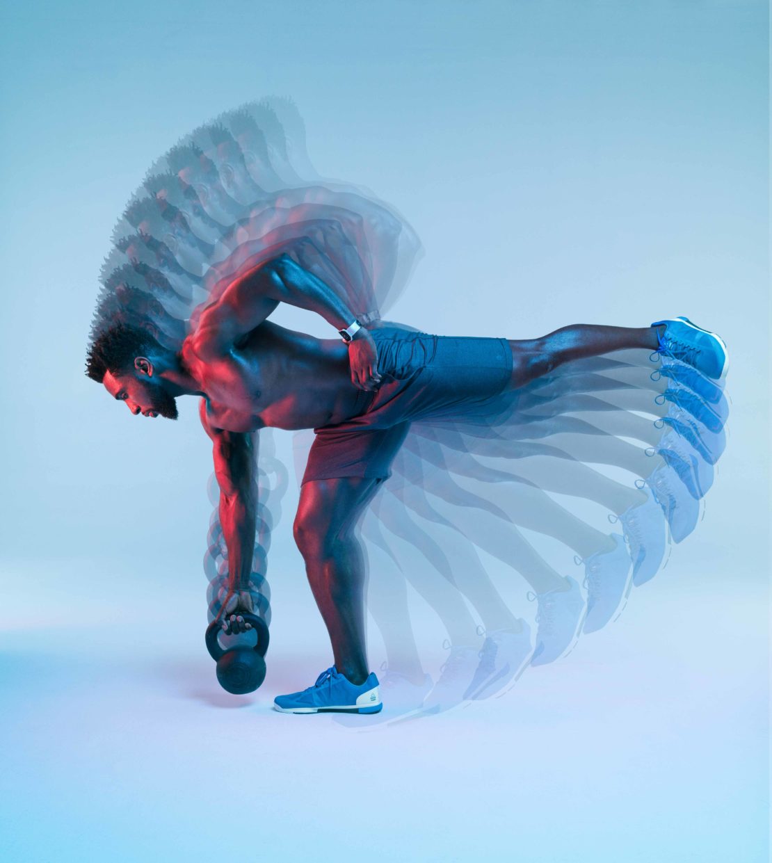 Athletic man performing single-leg deadlift exercise with kettlebell in a studio with light blue and red gradients, captured with motion blur.