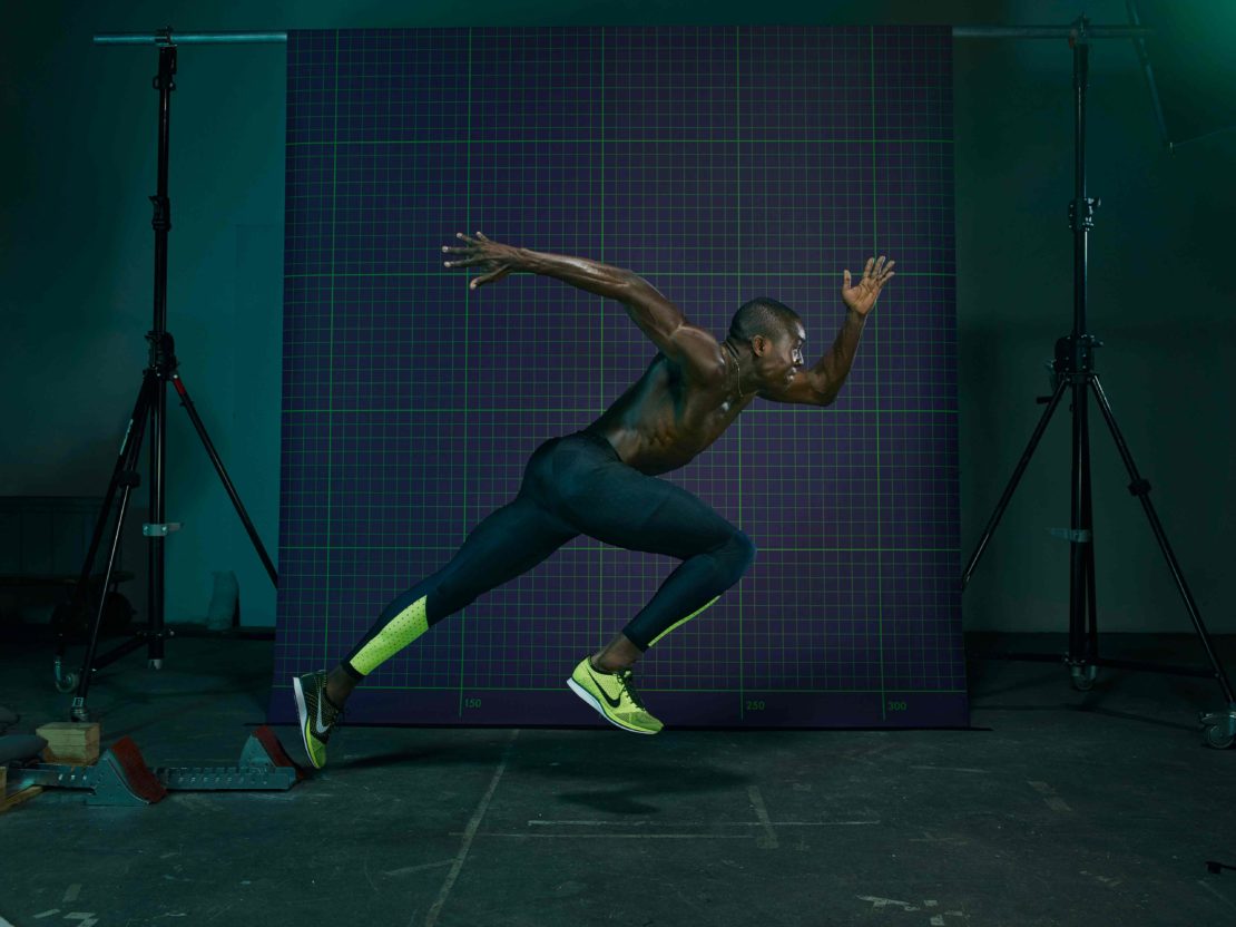 Athletic man in running pose in a photo studio. He is wearing sports gear and sprinting from a starting block, under studio lighting.