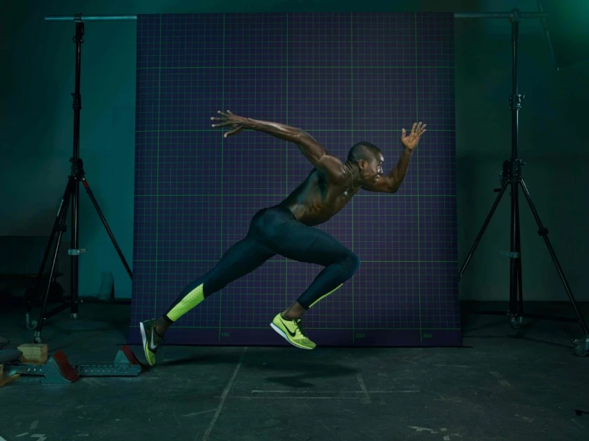 Athletic man in running pose in a photo studio. He is wearing sports gear and sprinting from a starting block, under studio lighting.