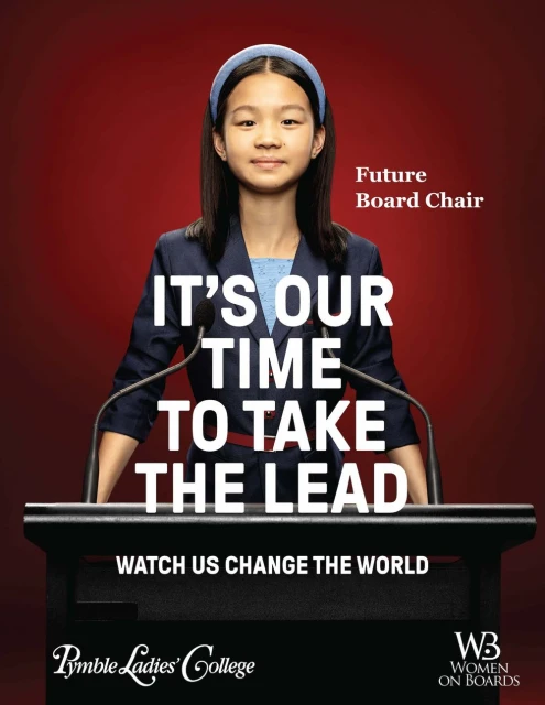 Portrait of a child at a podium in front of a red background with text promoting women on boards.  She is wearing a blazer and headband.