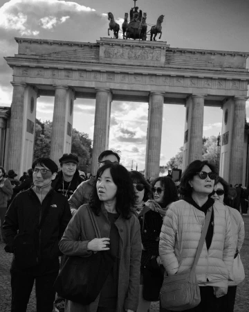 Monochrome shot of the Brandenburg Gate with people in the foreground, architectural landmark, historic site, and tourist destination.