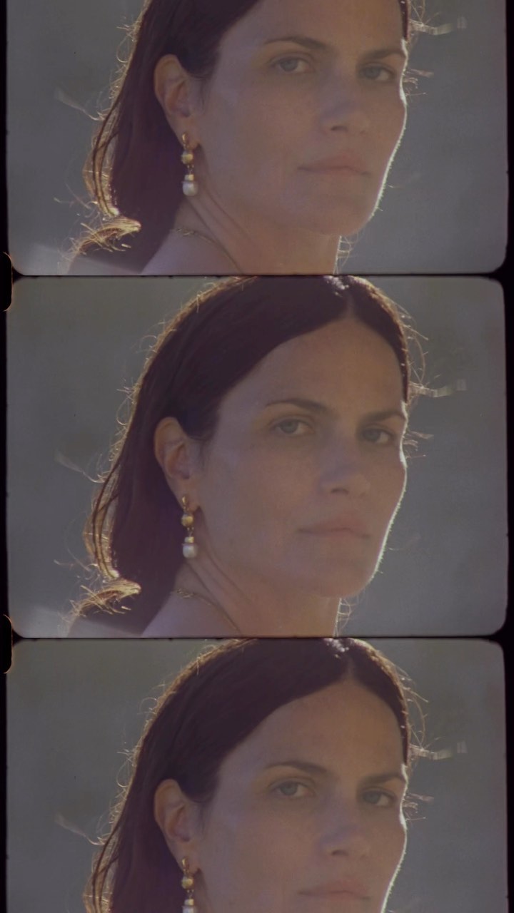 Portrait of a woman with dark hair and pearl earrings, lit by natural light, wearing a simple top, in a triple exposure effect.