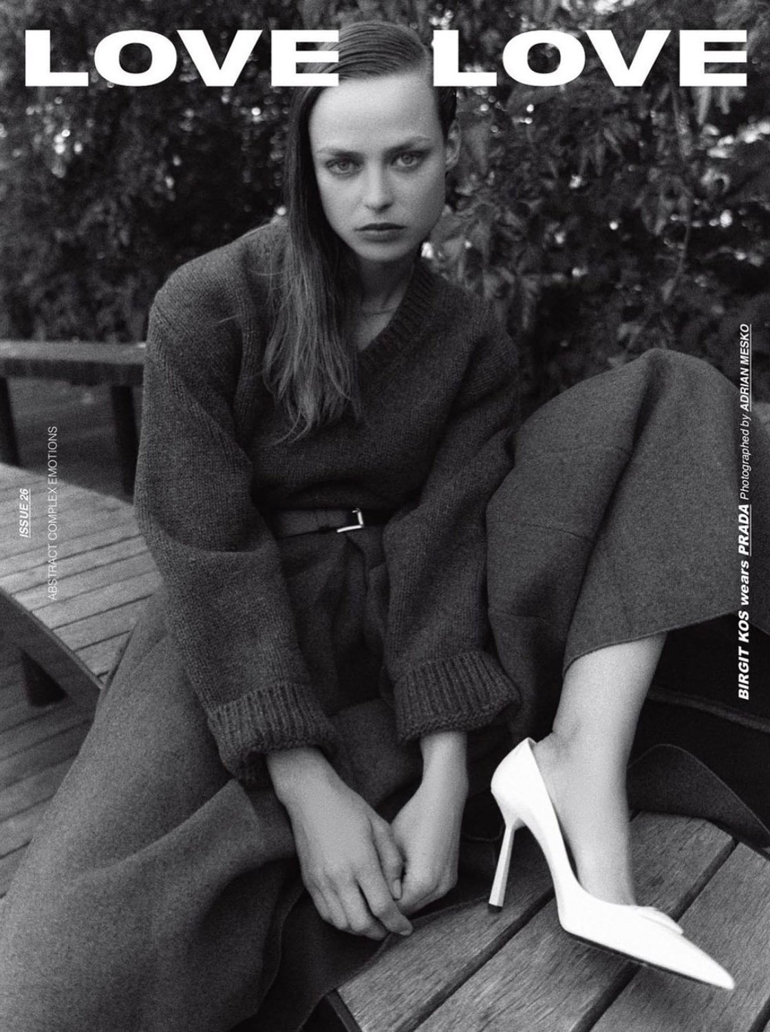 Black and white fashion shot of a woman wearing Prada on a wooden surface with foliage in the background and the word 'LOVE' above.
