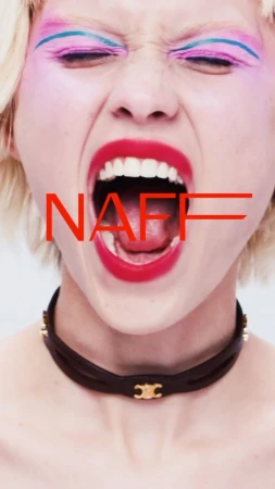 Close-up portrait of a woman with vibrant pink eyeshadow, blue eyeliner, and bright red lipstick yelling with her mouth wide open, wearing a black leather choker.