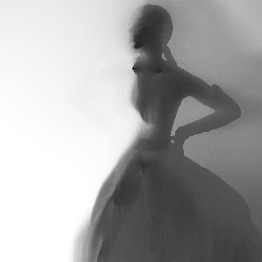 Monochrome portrait of a model with blurred motion effects against a bright gradient background.