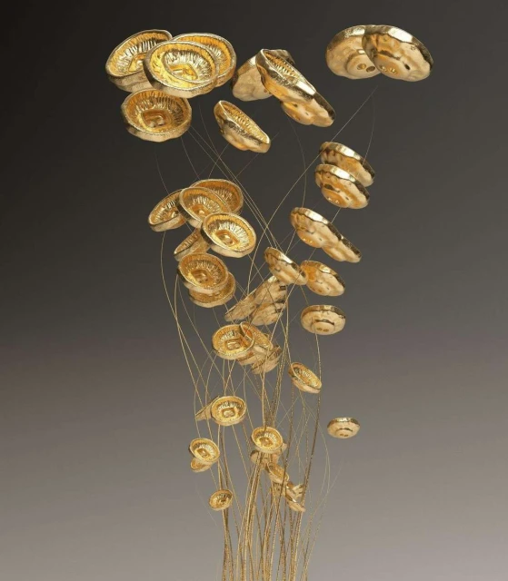 Artistic composition featuring golden, circular ornaments suspended by delicate, thin strands against a gradient grey background.