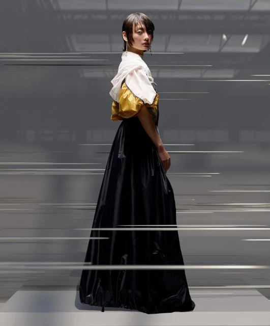 A woman poses in an oversized gown featuring a white bodice and black skirt in a studio environment, with motion-blurred lines creating a dynamic effect.