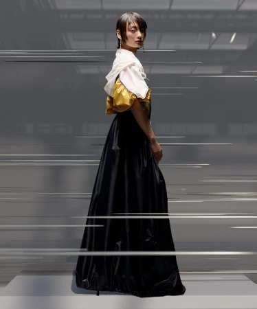 A woman poses in an oversized gown featuring a white bodice and black skirt in a studio environment, with motion-blurred lines creating a dynamic effect.