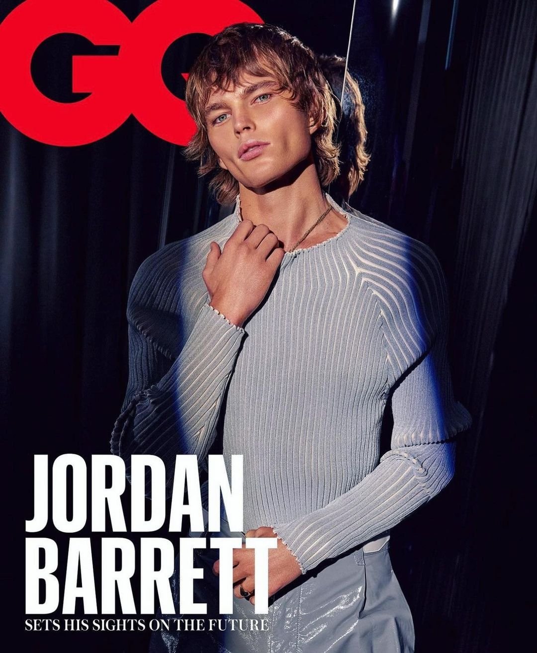 GQ magazine cover featuring male model Jordan Barrett wearing a light blue knit top and light blue pants against a dark background.