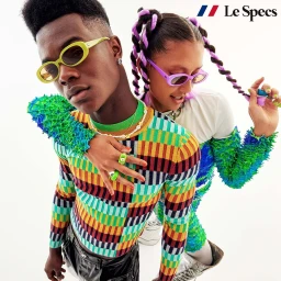 Two models wearing colourful patterned knitwear and vibrant sunglasses against a bright white background