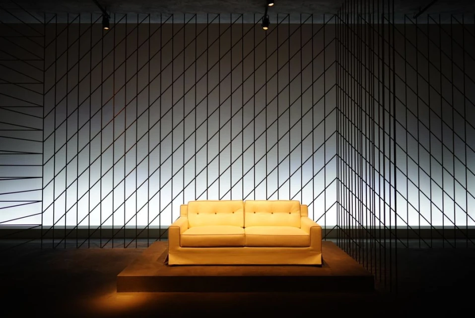 Contemporary living room features a modern yellow sofa on a platform against a wall with a geometric black line pattern.