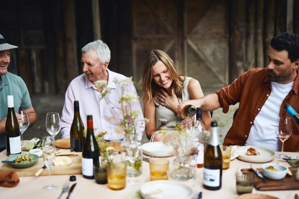Four people around a table enjoying wine, food, and conversation in a rustic setting, creating a warm and inviting atmosphere.