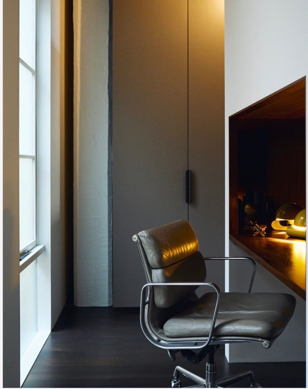 Interior scene featuring a leather office chair with chrome frame, next to a window and built-in shelf with decor.