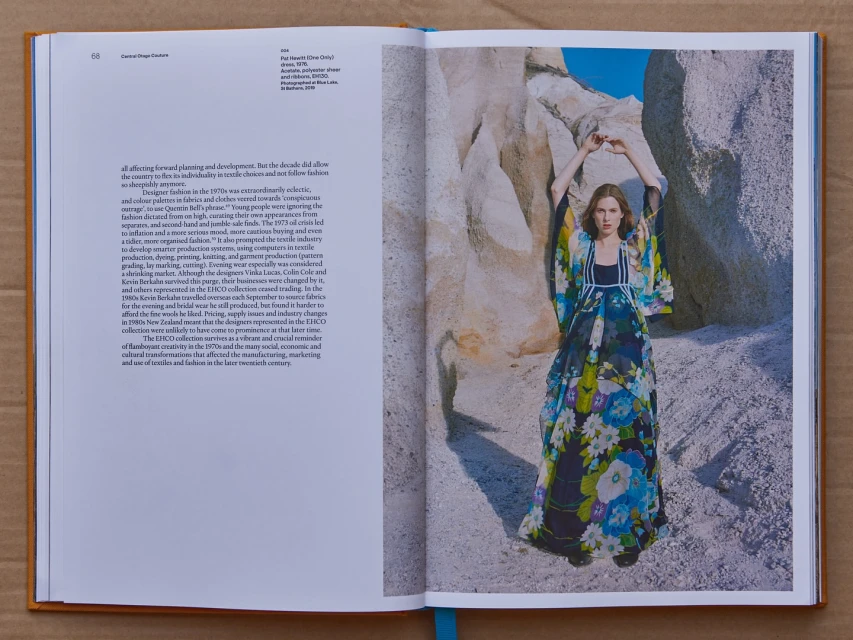 Fashion editorial in open book features a woman in a floral dress, standing amid rock formations under a clear sky, artistic layout.