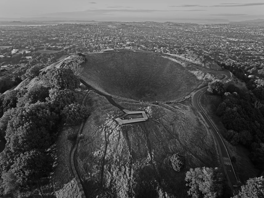 Aerial view of Rangitoto Island in Auckland, New Zealand, with its volcanic cone and surrounding urban landscape on the horizon.