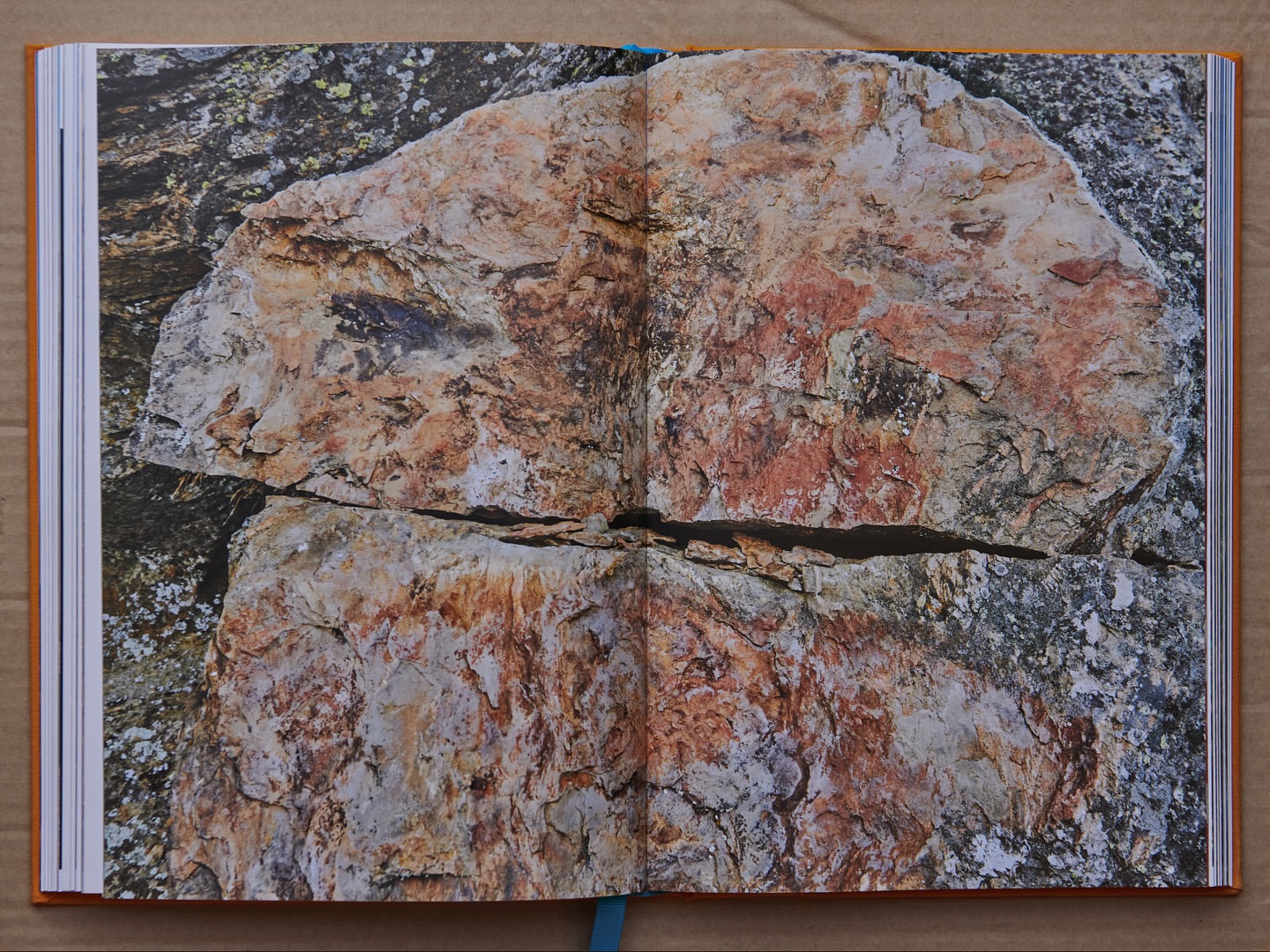 Open book with a photo of a large rock formation with reddish-brown hues and textures displayed across a double-page spread.
