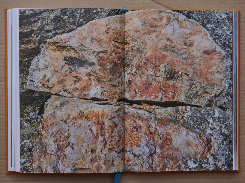 Open book with a photo of a large rock formation with reddish-brown hues and textures displayed across a double-page spread.