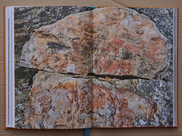 Open book with a photo of a large rock formation with reddish-brown hues and textures displayed across a double-page spread.