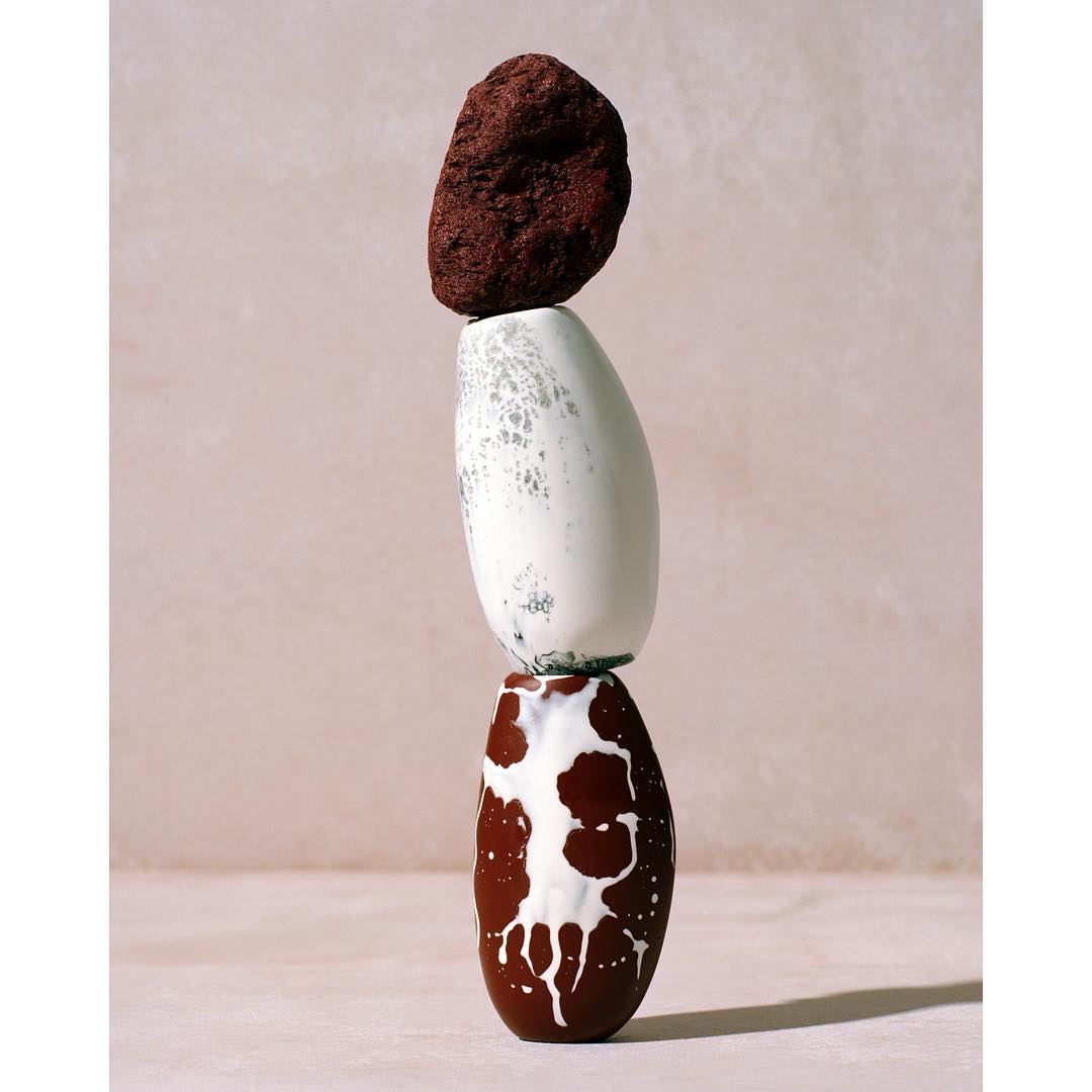 Still life of balancing stones and vases, showcasing earth tones and neutral backdrop, promoting a zen-like aesthetic with a smooth surface.