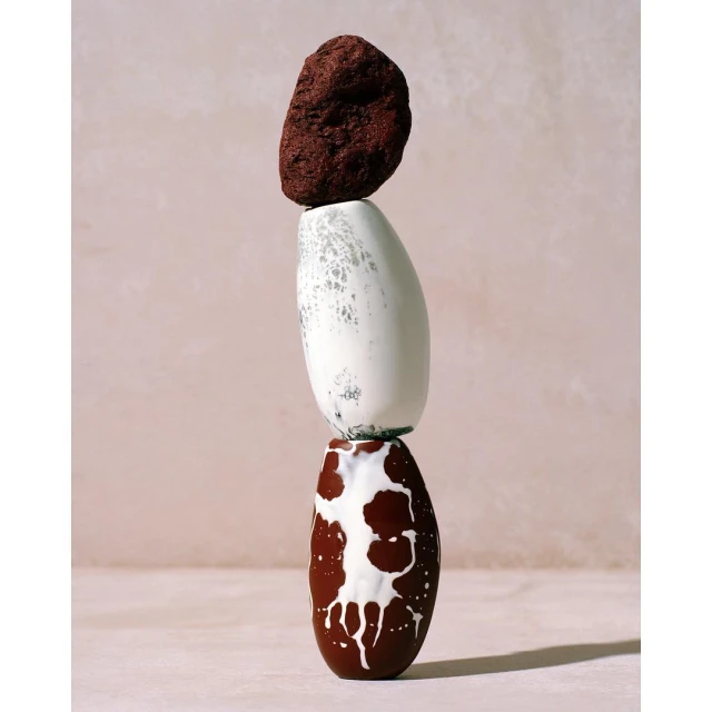 Still life of balancing stones and vases, showcasing earth tones and neutral backdrop, promoting a zen-like aesthetic with a smooth surface.